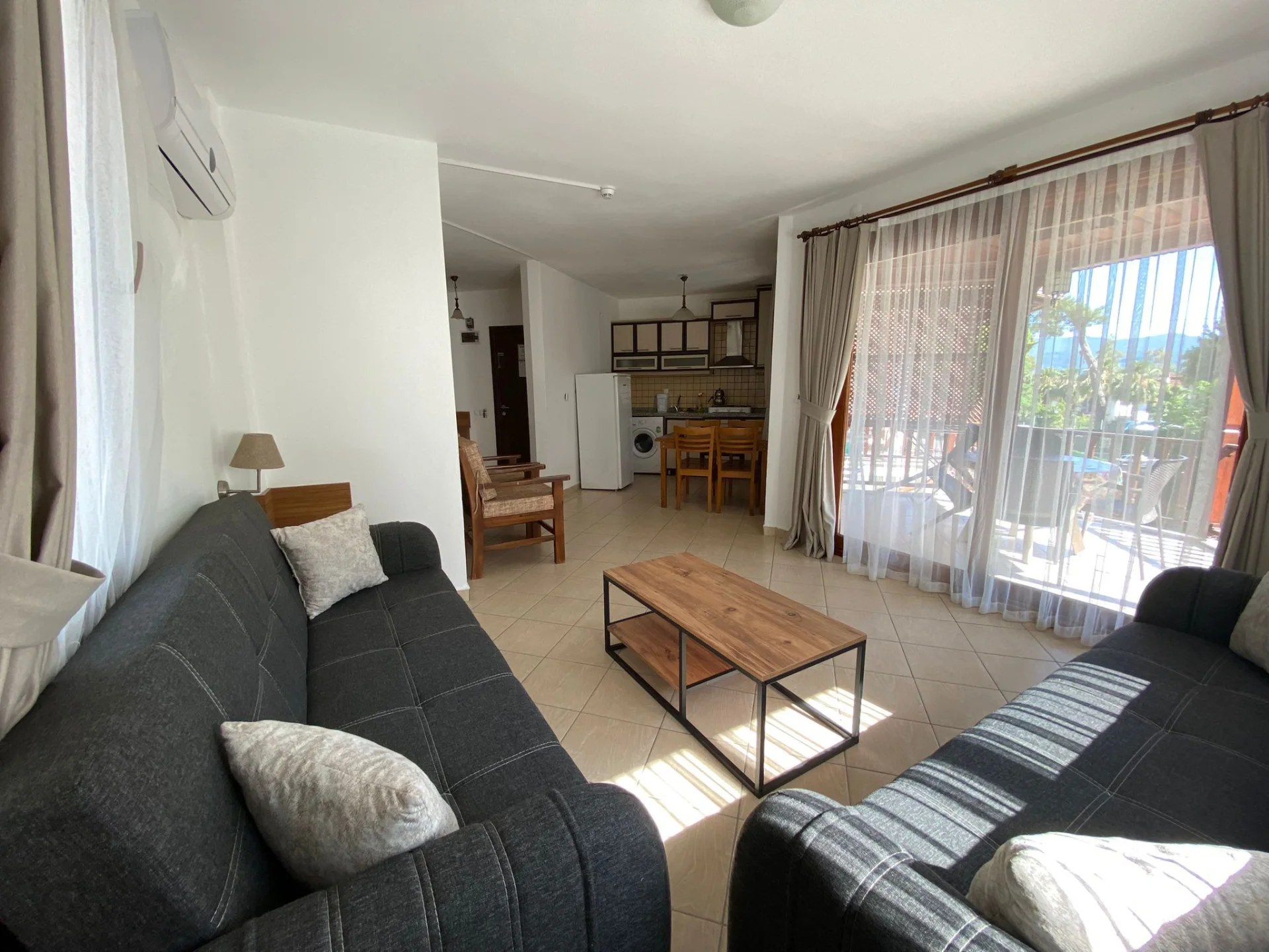 1+1 daire salon ve mutfak alanı; geniş oturma düzeni, balkon çıkışı ve gün ışığı